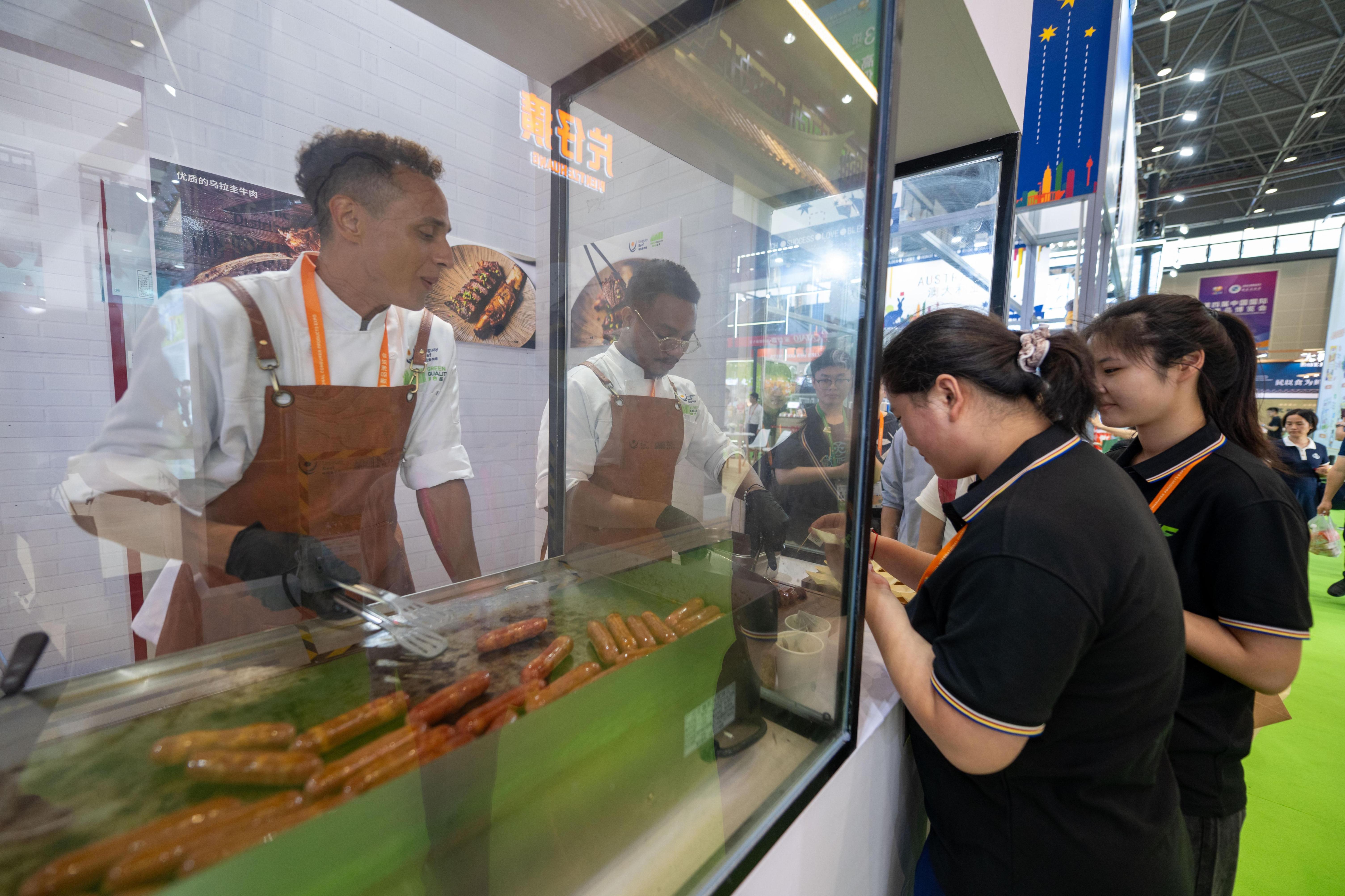 在高端食品保健品展区，参观者正在排队试吃来自乌拉圭的牛肉肠。人民网记者 翁奇羽摄